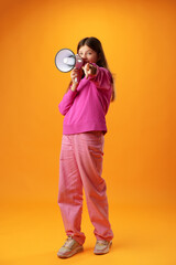 Teen girl making announcement with megaphone on yellow background