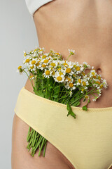 Young woman with daisies near the body, intimate hygiene and health