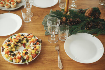 Christmas table setting. Modern salad with salmon as christmas wreath, appetizers and starters, glasses and cutlery on wooden table with fir branches and pine cones. Holiday arrangement and fest