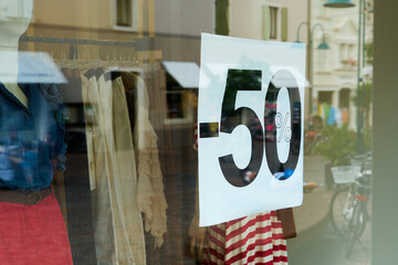 Hinweis auf im Preis reduzierte Bekleidung an einem Geschäft in der Altstadt von Riva del Garda in Italien - 641756995