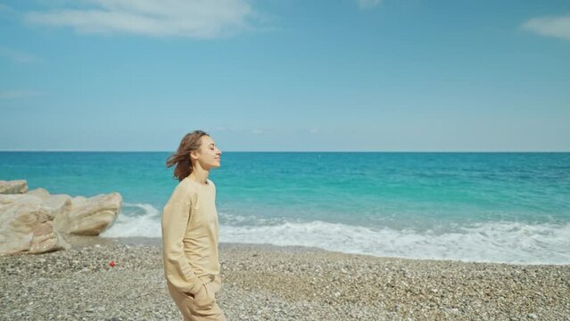 Outdoor portrait beautiful summer woman walking pebble beach and enjoying weekend at seaside with cliffs by the sea coast.