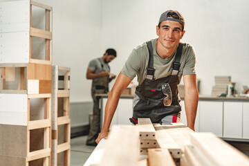 Portrait of young male carpenter standing in the wood workshop - obrazy, fototapety, plakaty