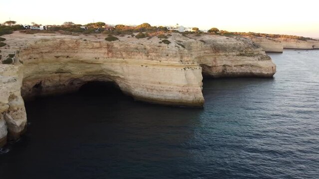 Drone Shoreline View of Benagil Caves of the Ocean Shoreline. Pan right of the calm sea water and rocky shore.