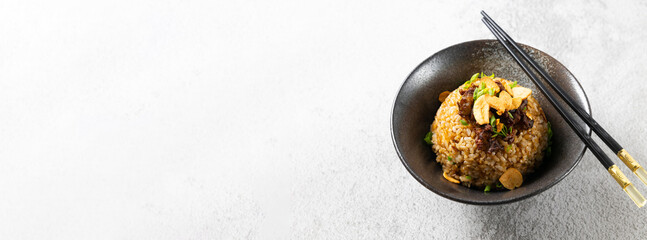 Japanese fried rice, Garlic fried, fried meat beef and spring onion vegetables in black bowl on table in asian restaurant