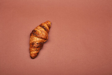 Croissant isolated on the bright solid fond plain red-brown background