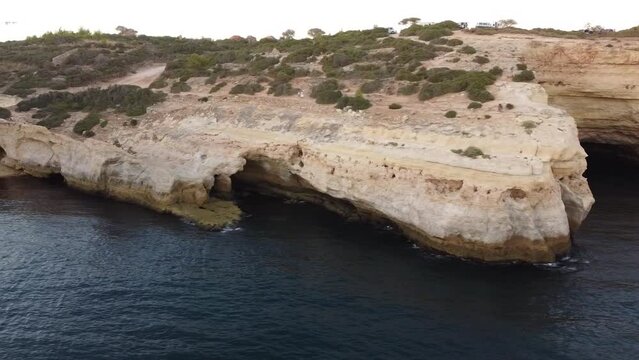 Clear Blue Water Aerial Landscape of the Benagil Caves in Lagoa Portugal. Left pan to the sandy beach from caves of the Portugal coastline.