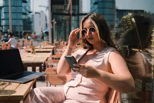 Tech Time in Style with Model Engaging with Phone Over Coffee in the City