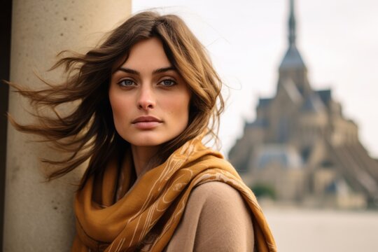 Photography in the style of pensive portraiture of a merry girl in her 20s wearing an elegant silk scarf at the mont saint-michel in normandy france. With generative AI technology