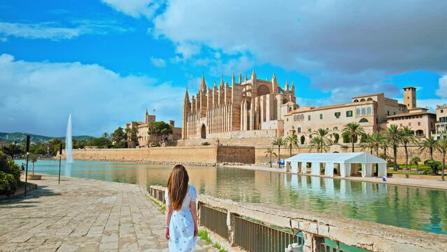 Beautiful girl tourist walking by iconic landmark in Palma Capital of Majorca. A female exploring Catedral de Mallorca and Spanish architecture in Mallorca, Balearic Islands, Spain