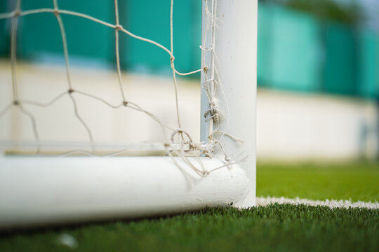 Close-up at football goal post structure which is placed on artificial turf ground pitch. Sport equipment object photo.