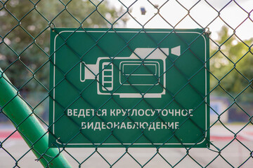 On the metal green fence there is a sign 