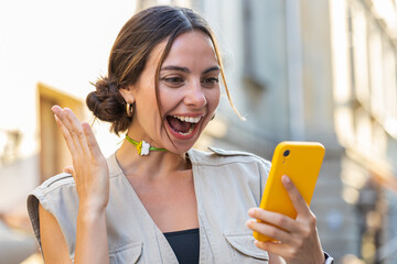 Pretty young woman use mobile smartphone celebrating win good message news, lottery jackpot...
