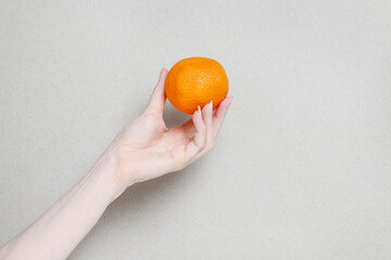 A woman holds a juicy tangerine in her hand.