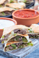 Mexican fajita quesadilla with pieces of beef steak, bell pepper, onion and cheese, on wooden board