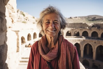 Naklejka premium Environmental portrait photography of a happy mature woman wearing a trendy off-shoulder blouse at the crac des chevaliers in homs governorate syria. With generative AI technology