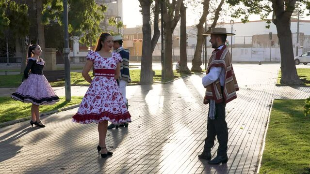 Adult men in huaso costumes lead the women by the arm to dance the cueca