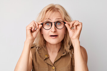 Portrait of 50 year old lady squinting in glasses isolated on white studio background. Vision check...