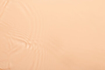 Water beige surface abstract background. Waves and ripples texture of cosmetic aqua moisturizer with bubbles.