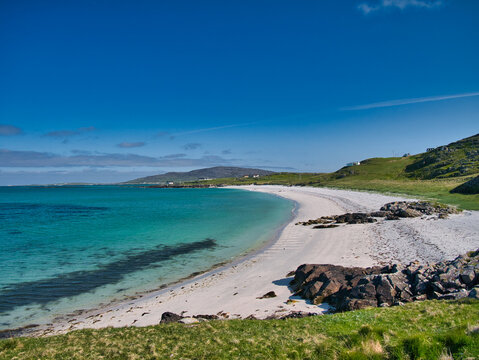 The white sand and turquoise waters of Traigh Leis on the island of Eriskay in the Outer Hebrides, Scotland, UK. Taken on a sunny morning in summer with blue sky and light cloud.