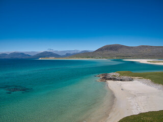 Two distant people on a white sand beach in Luskentyre Bay on the coast of the Isle of Harris,...