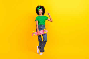 Full body portrait of cheerful friendly schoolgirl hold skateboard empty space isolated on yellow color background