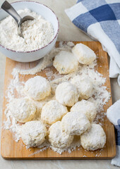 The process of making cheesecakes. A blank for cheesecakes on a board in flour, a kitchen towel and a bowl of flour..
