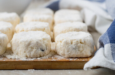 The process of making cheesecakes. Cheesecakes lie on a board with flour, close, macro, horizontal