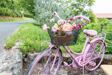 a pink bicycle on a green background with a basket of colorful flowers