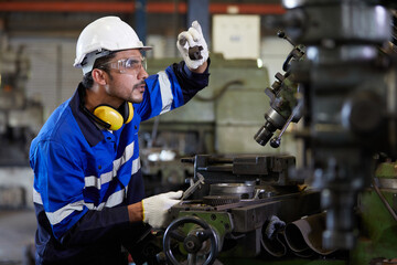 factory worker or technician looking and checking screw beside lathe machine in the factory