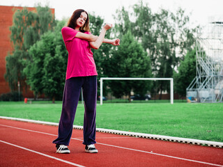 Obraz premium Young teenager girl doing stretching exercises on a running track. Selective focus. The model is slim body type. Light and airy look. Get ready for sport concept. Outdoor activity and lifestyle.