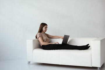 Young woman is sitting on a sofa with a laptop. Concept online session with a psychologist