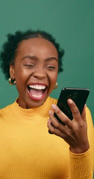 Young Black woman reads text message shocked excited, green studio background