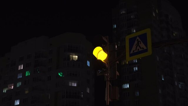 Switching traffic light at night intersection in city. Concept. Changing traffic lights for cars in night city. Glowing traffic light changes lights at intersection of night city