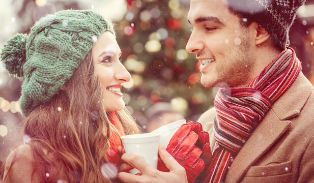 couple, man and woman, on a christmas market in winter drinking hot spiced wine, looking at each other with love