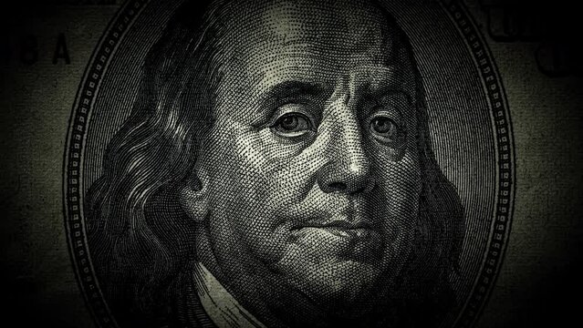 The portrait of Benjamin Franklin on the 100 US dollar bill is a close-up that gradually darkens and the eyes begin to glow. The idea of a conspiracy theory. 4k concept video.