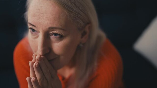 Stressed woman in her 50s praying, putting hands together, asking God for help