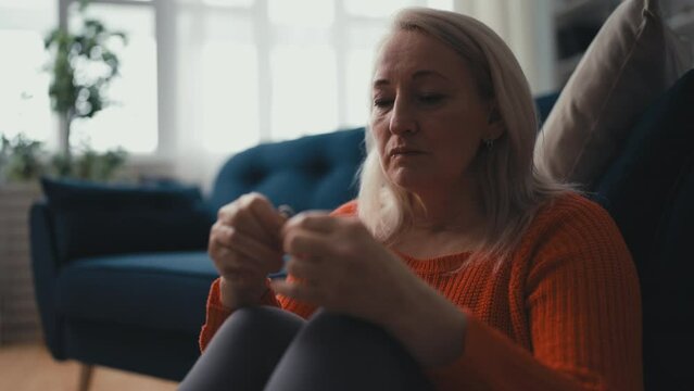 Mournful widow in her 50s holding wedding ring and crying, personal tragedy
