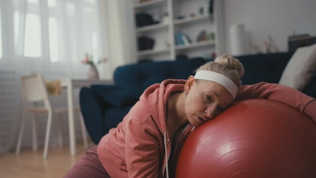 Middle aged woman feeling tired after active training with fitness ball, fatigue