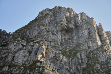 Shot capturing the beautiful mountain terrain in Bucegi National Park at sunset. Mountain landscape with green meadow and sharp rocks.