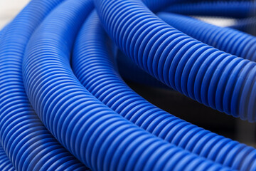There is a blue corrugated pipe on the construction site. The texture of the pipe close-up