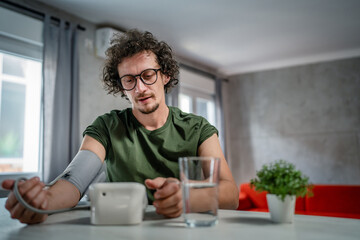 one adult caucasian man measure check blood pressure at home alone