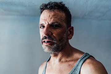 Bearded adult man in mouth guard in room with blue wall in daylight