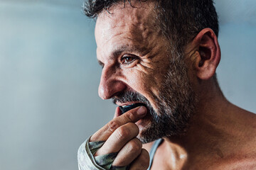 Adult crop man adjusting double braces mouth guard with taped hand in daylight