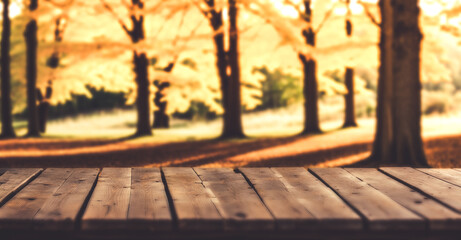 Fototapeta premium Empty wooden table foreground. Idyllic autumn park with yellow foliage in background. Floral fall season concept. Product display for advertising.