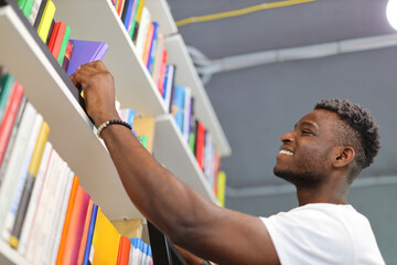 A young man in a library, studying amidst books, seeking knowledge for personal growth.