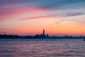 Amazing sunset view with orange sky and black clouds over city buildings in evening daylight