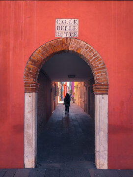 Unrecognizable lady walking in corridor of building with arched entrance