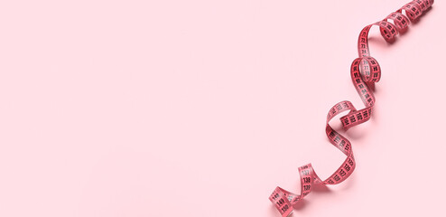 Measuring tape on pink background with space for text