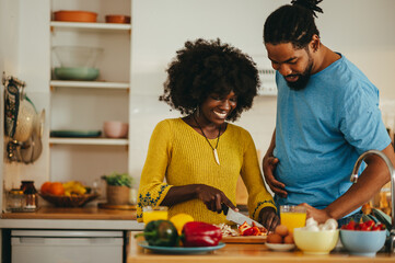 A happy multicultural couple is cooking dinner together at home.