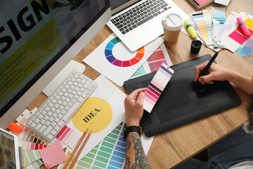 Male graphic designer working with tablet and color palette in office, closeup